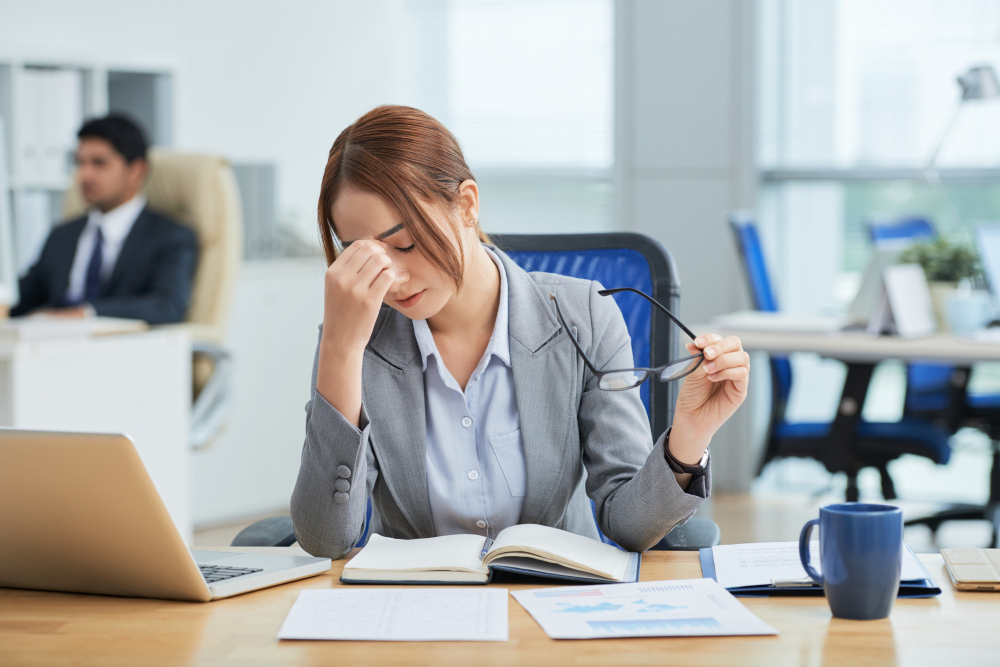 medium-shot-young-asian-woman-sitting-desk-office-rubbing-nose.jpg